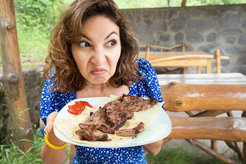 Woman sniffs a spoiled steak in a restaurant. The concept of suffering from anorexia or an eating disorder and loss of sense of smell after covid.