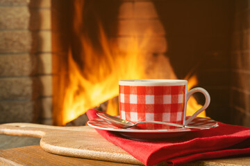 A cup with tea or coffee before a cozy fireplace, in a country house.