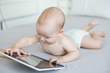 A six-month baby with a tablet computer, looking at screen, at home