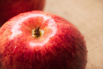 Close-up of a red apple that is wet in water. Viewed from the side, blurry light background. The red apples are very tasty.