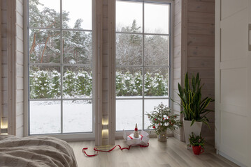 Scandinavian living room interior in a wooden house. Christmas room decoration, Christmas tree and gift, large window