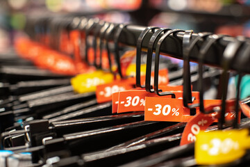Discount sale tags 30% off, on hangers with clothes in casual, home or sport clothing store. Fashion concept, discount season, black friday, offline shopping, gimmicks, holiday sales. Side view