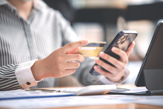 female hand holding phone and credit card