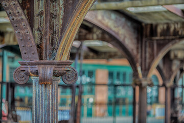 Rusting iron steel girders with intricately carved columns in an abandoned train station