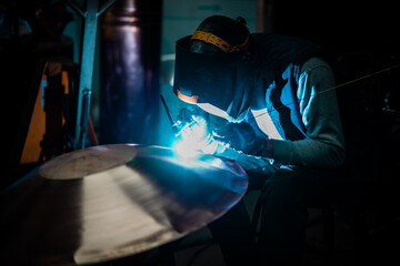 Heavy industry worker welding steel with electric appliance.