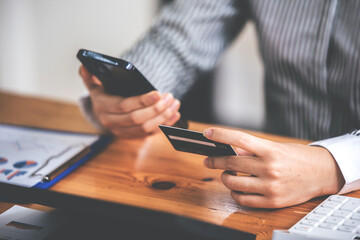 female hand holding phone and credit card