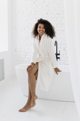 Afro american woman sitting on tub in bathroom