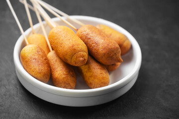 Corn dogs cooked with sausage and dough on a dark background - obrazy, fototapety, plakaty