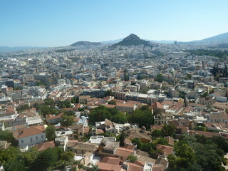 Fototapeta na wymiar La célèbre ville d'Athènes, grande agglomération avec ses maisons blanches, et sa végétation torride, ainsi que ses monts tout autour, sous un beau jour