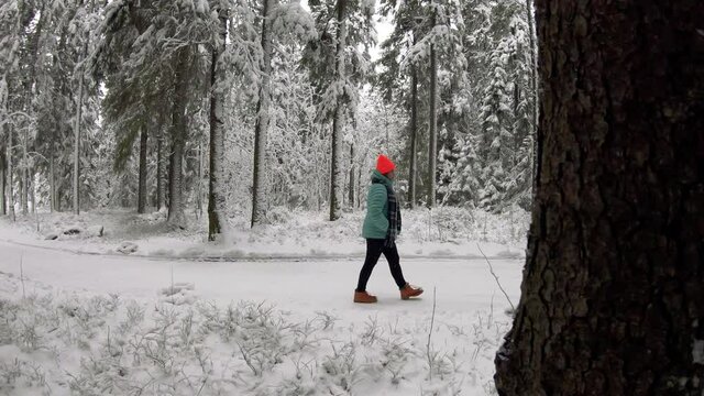 A woman enjoying the snow landscape in the woods. Cheerful girl enjoying beautiful winter day. Carefree lady having joyful emotions outdoor. Winter concept. 4K Slow motion.