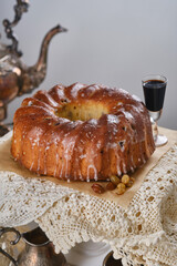 Grandma's recipe. Homemade Bundt cake or pound cake with sugar glaze on an antique napkin or tablecloth against blurred vintage dishes. Shallow depth of field