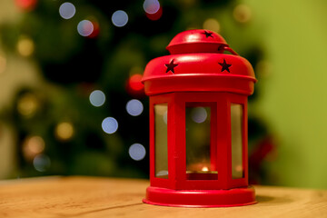 Red lantern in front of blurred Christmas tree, festive background, concept of hope