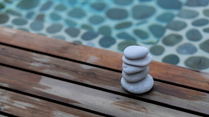 Zen stones tower. White spa stones with leaves on blurred blue background.