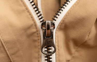 Close-up zip lock on light-colored clothing, jacket. Zipper closure with lock. © Gudman