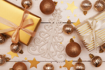 Fototapeta na wymiar Christmas decorative composition with gold shiny snowflakes, christmas golden balls, gift boxes on rustic white wood background. Christmas or New Year concept. Festive Christmas background 