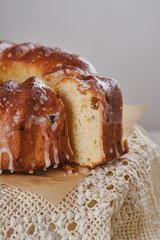 Homemade Bundt cake or pound cake with sugar glaze on an antique napkin or tablecloth against blurred vintage dishes. Shallow depth of field