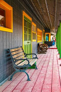 Colorful western proch on commercial building with vintage benches and a muddy red plank floor and green and yellow trim - vanishing perspective and selective focus
