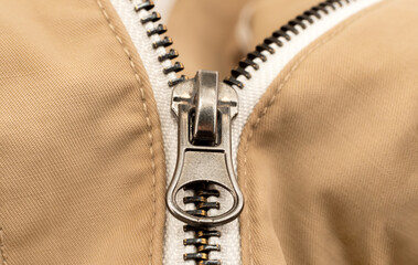 Close-up zip lock on light-colored clothing, jacket. Zipper closure with lock.