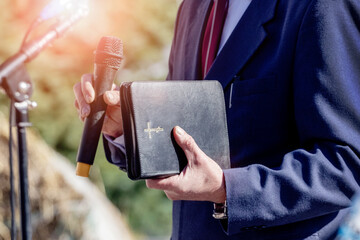 Pastor with a Bible in his hand during a sermon. The preacher delivers a speech