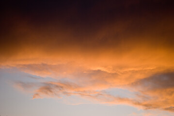 Sunset skies with thunderstorm clouds highlighted with orange hues 