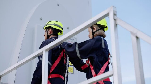 Two maintenance engineers in safety gear working at height inspect safety gear working at height for readiness and safety before starting work, clean energy concept, renewable energy, save the world.
