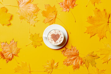 Cup of coffee with heart shape and maple leaves around