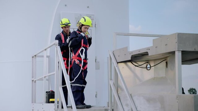 Two maintenance engineers in safety gear working at height inspect safety gear working at height for readiness and safety before starting work, clean energy concept, renewable energy, save the world.
