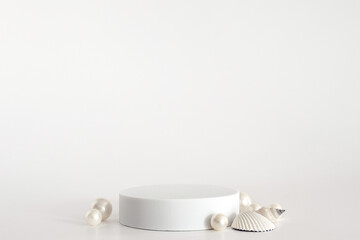 White podium with pearls and shells on the white background, simple geometric form. Podium for...