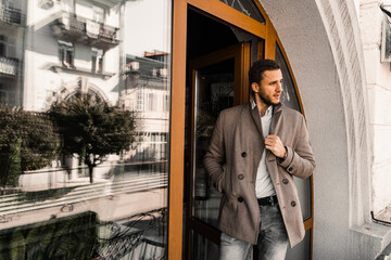 Handsome bearded business man in coat posing outside. Male lifestyle.