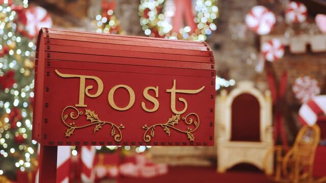 Closeup Red post box for letters to Lapland to Santa Claus. Christmas tradition. Decorative mailbox Santa Claus workshop, wrapped gifts presents boxes on holiday eve in night on xmas background