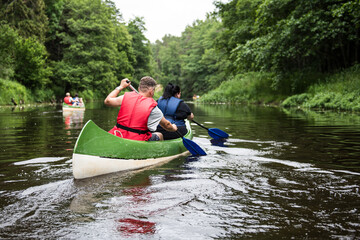 People canoeing on Irbe river, peaceful nature scene, Latvia.