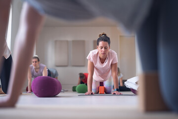 Obraz premium Woman doing a yoga pose with concentrated expression in a class