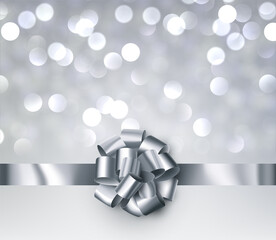 Silver foil ribbon with beautiful bow on grey bokeh background.