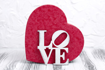 Red box in the shape of a heart with a wooden inscription on a white background. Valentine's day greeting card.
