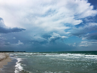 stormy dramatic beautiful clouds  over the sea, green water and white sandy beach, copy space