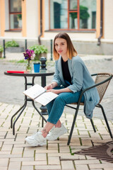 Confident beautiful girl with a notebook on the terrace. Business style. Psychologist