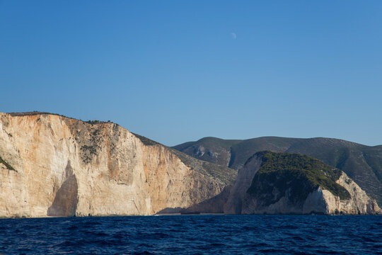 Panorama of the island shore with impenetrable clifs surrounding a sandy beach with a wrecked transport ship