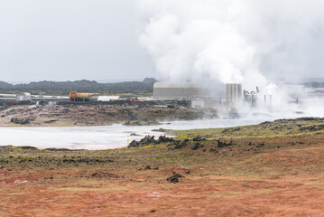 Fototapeta na wymiar Geothermal power station shrouded in steam in a volcanic landscape in Iceland on a foggy day