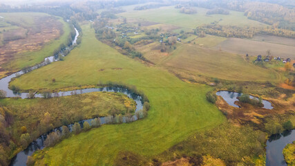 Top view autumn landscape with yellow trees on bank of small river. Nature concept.