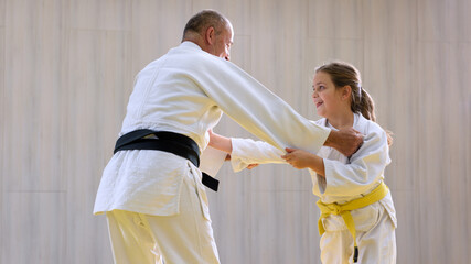 Young female judo girl practicing with old judo teacher