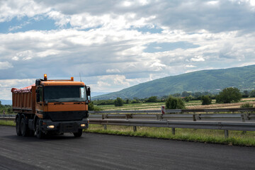 A large and heavy dump truck is parked on the highway.