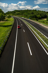 Fototapeta premium The red car is driving on the new highway. Red car driving along highway.