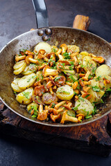 Traditionelle frische Pfifferlinge mit Bratkartoffeln und Petersilie serviert als close-up in einer klassischen Bratpfanne