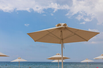 Beautiful view of white sand beach with sun umbrella and sunbed. Greece.