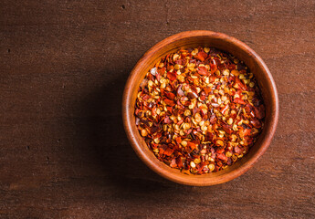 Pimento chili flakes bowl copy space dark wood background.