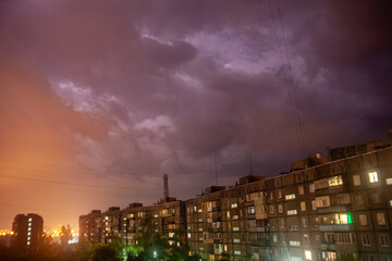 Lights of windows on the ground, fire of lightning in the sky