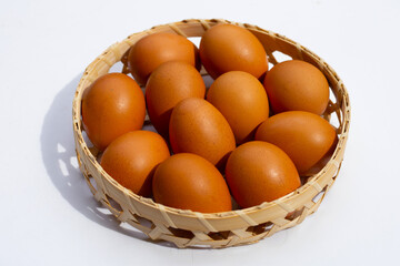 Chicken eggs in bamboo basket on white.