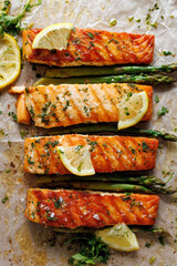 Grilled portions of salmon and green asparagus with lemon slices and herbs, top view - 468854820
