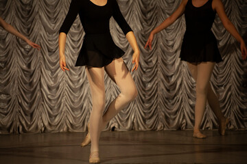 Dancer on stage. Girl in a black dress and Beige tights, front view.