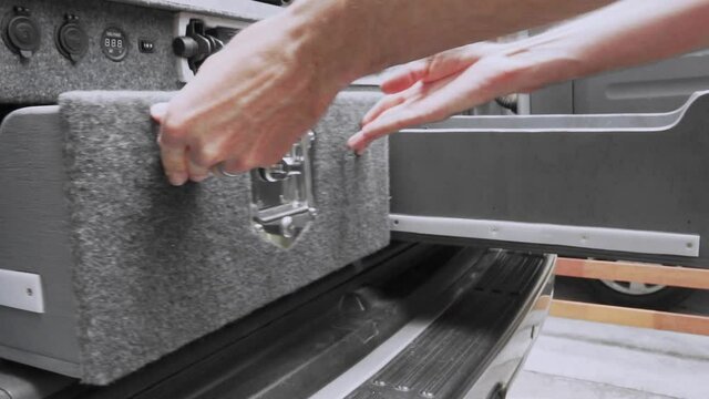 Man closes and locks storage drawers in back of SUV camper van
